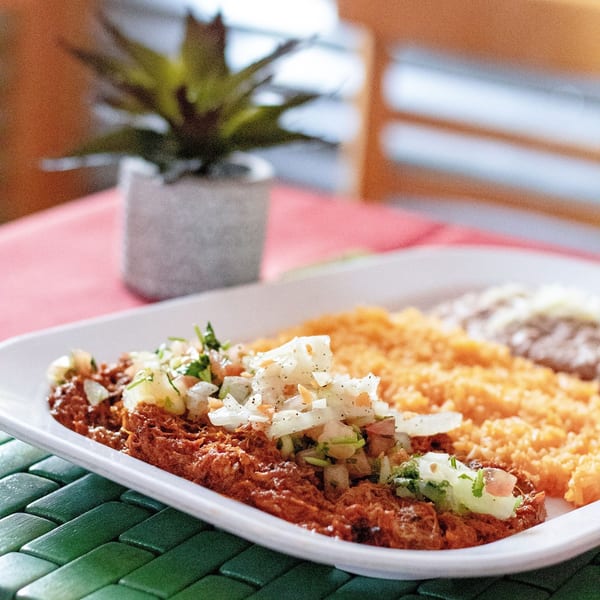 A plate of Mexican food with shredded meat, rice, and beans, topped with fresh salsa.